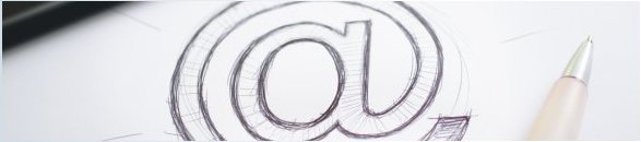Skizze eines At-Zeichens auf Papier neben einem Stift