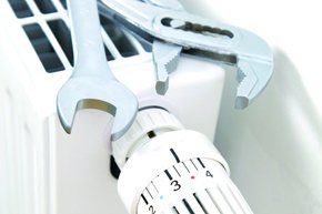 Schraubenschlüssel und Thermostatventil an einem Heizkörper